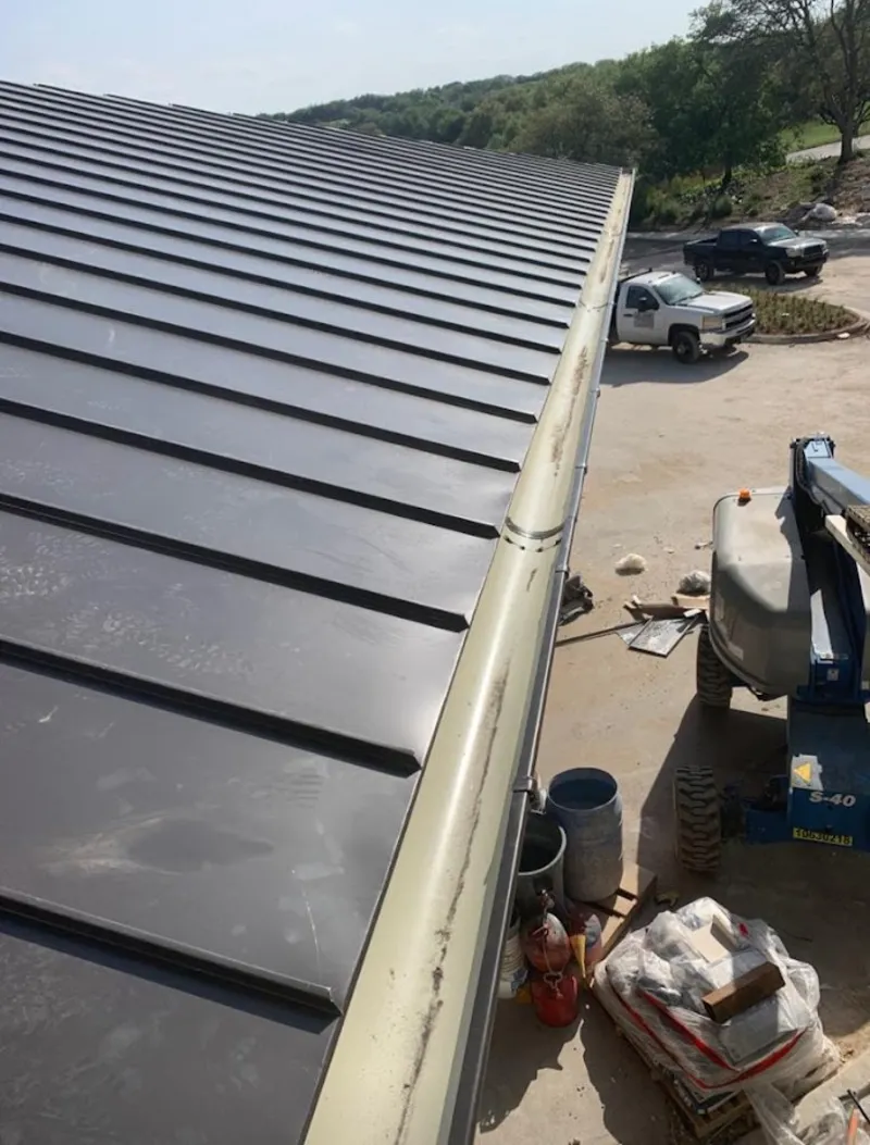 Standing seam panel and gutter detail on a metal roofing jobsite in Machesney Park